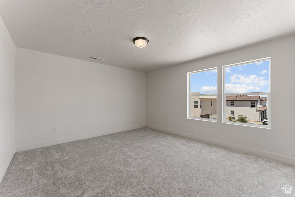 Carpeted spare room featuring baseboards and a textured ceiling