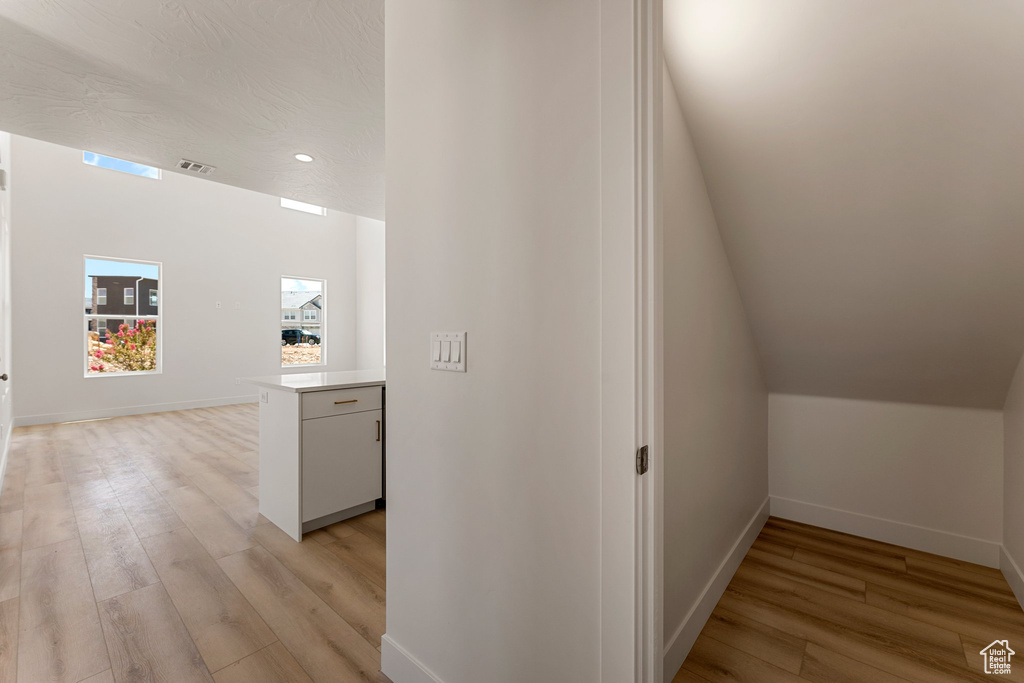 Hallway with light wood-type flooring and recessed lighting
