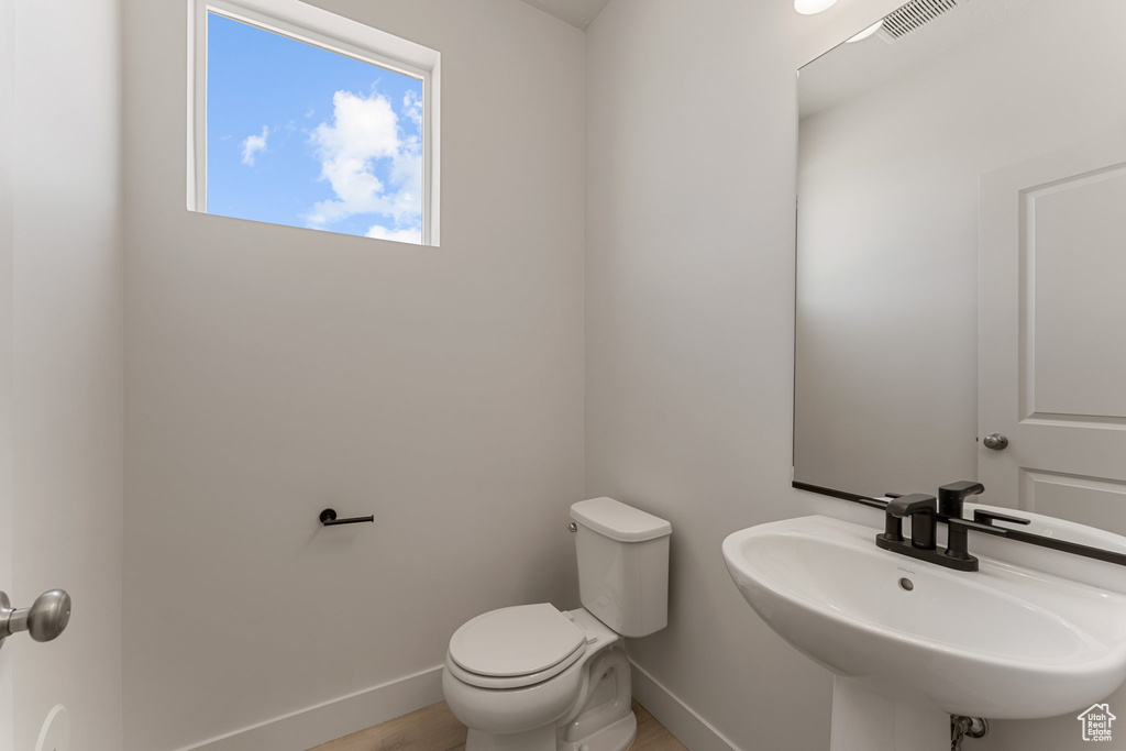 Half bath with a sink and wood finished floors