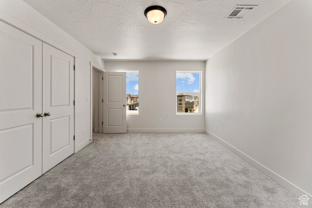 Unfurnished bedroom with carpet flooring, a textured ceiling, and a closet