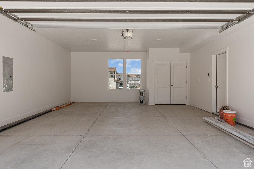Garage featuring electric panel and baseboards
