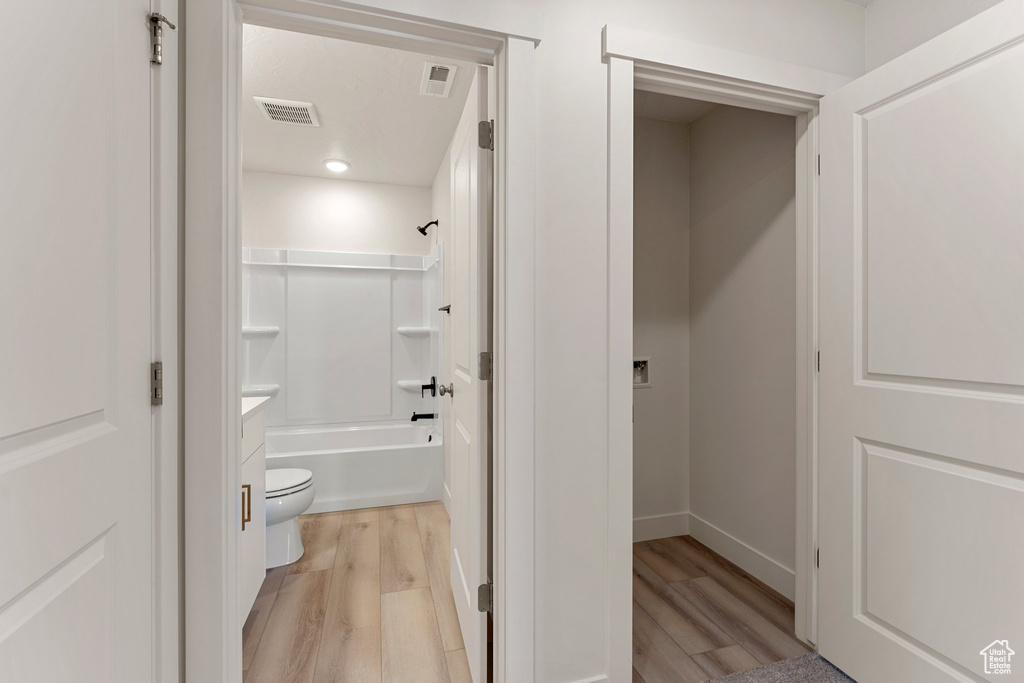Full bathroom with wood finished floors, vanity, shower / bath combination, and recessed lighting