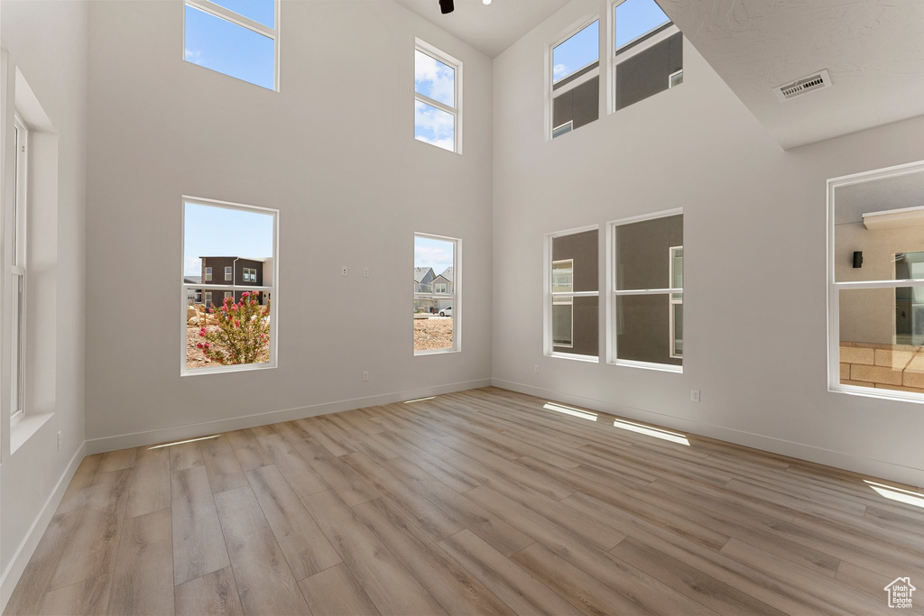 Spare room featuring wood finished floors and a towering ceiling