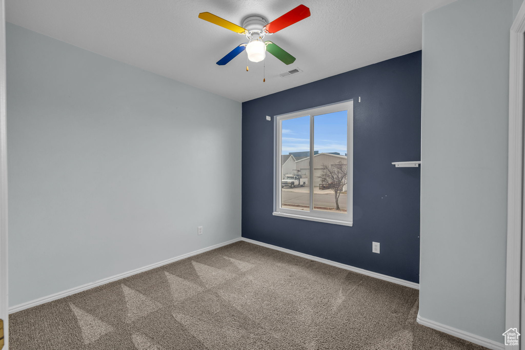 Carpeted empty room featuring a ceiling fan, baseboards, and visible vents