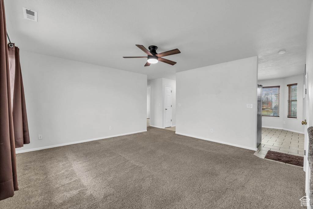 Carpeted spare room with baseboards, ceiling fan, and visible vents