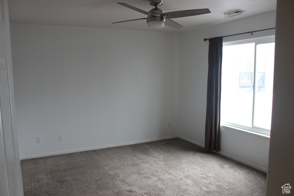 Carpeted empty room with baseboards, ceiling fan, and visible vents