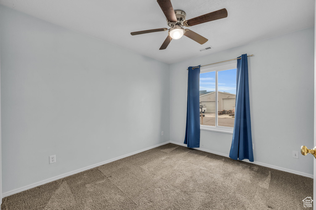Unfurnished room featuring a ceiling fan, carpet floors, baseboards, and visible vents