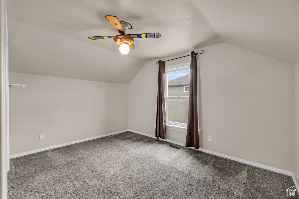 Additional living space featuring carpet flooring, visible vents, baseboards, ceiling fan, and lofted ceiling