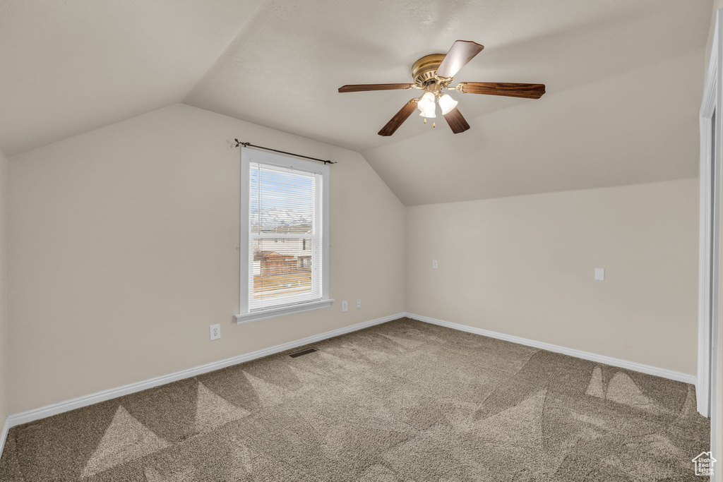 Bonus room featuring carpet flooring, visible vents, baseboards, ceiling fan, and vaulted ceiling