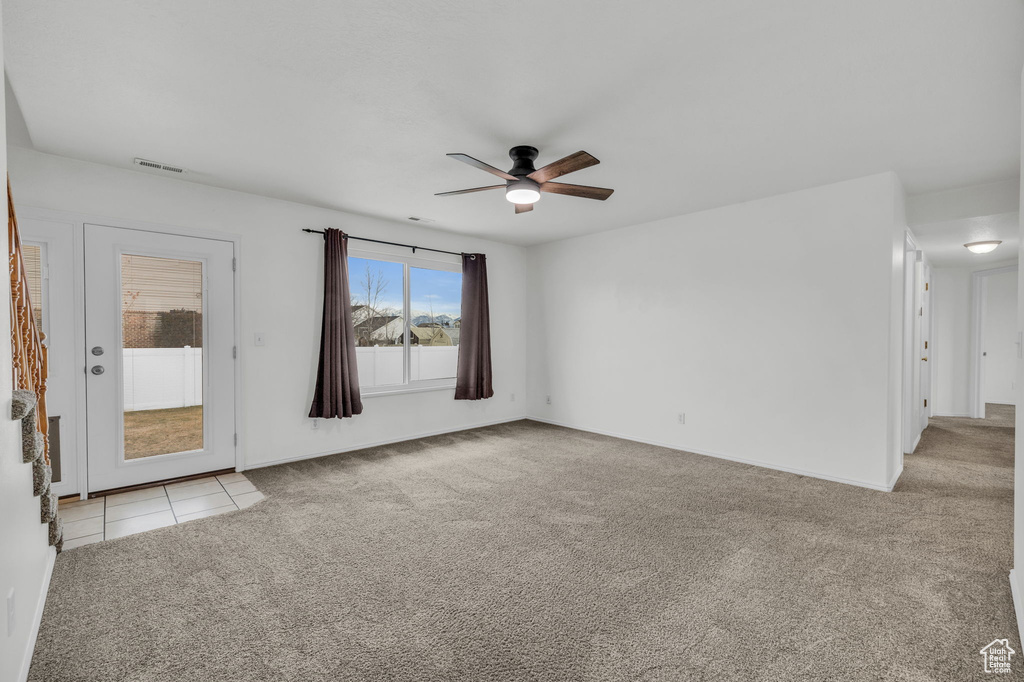 Unfurnished room with visible vents, baseboards, ceiling fan, light tile patterned floors, and light colored carpet