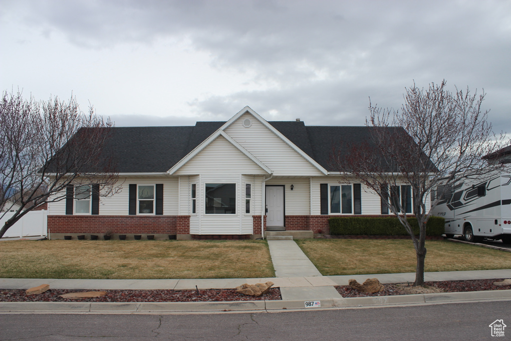 Ranch-style house featuring brick siding, a shingled roof, and a front lawn