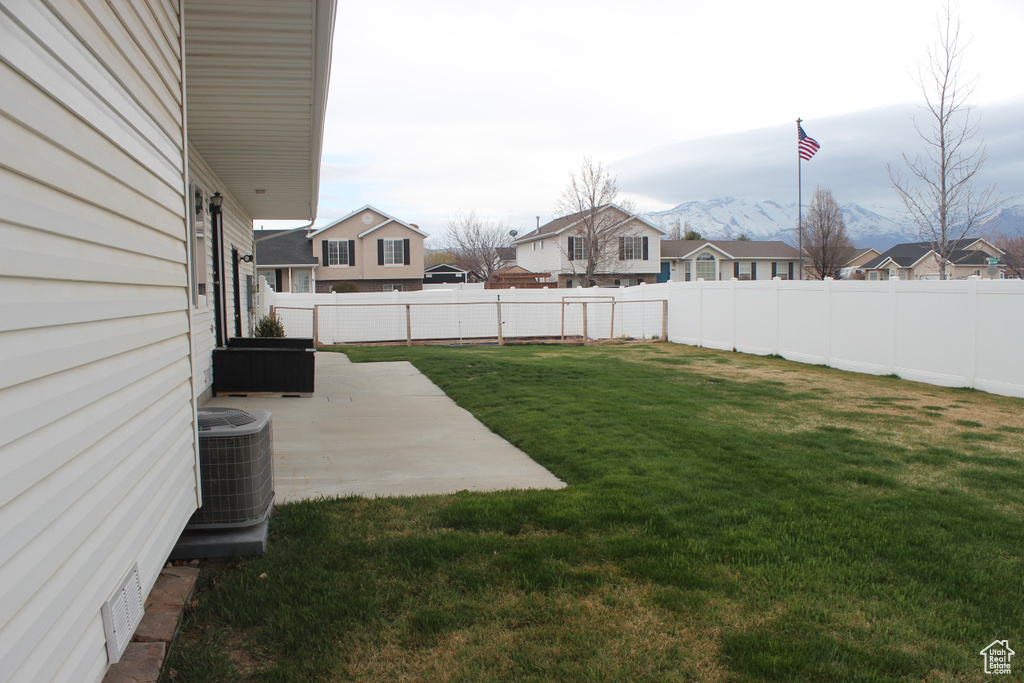 View of yard with a fenced backyard, central air condition unit, a residential view, and a patio area