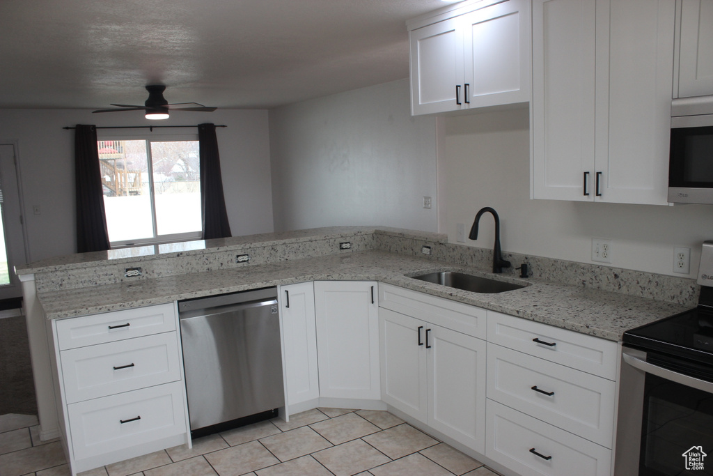 Kitchen with white cabinetry, a sink, ceiling fan, a peninsula, and appliances with stainless steel finishes