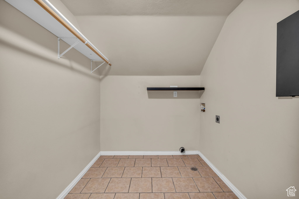 Laundry room featuring hookup for an electric dryer, light tile patterned floors, hookup for a washing machine, baseboards, and laundry area