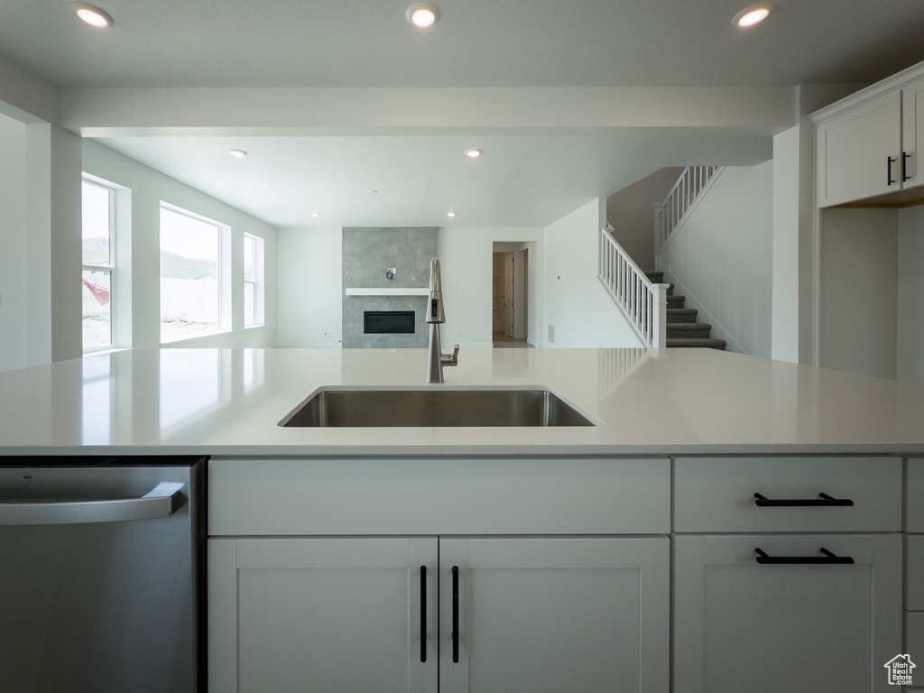 Kitchen featuring stainless steel dishwasher, a sink, open floor plan, recessed lighting, and light countertops