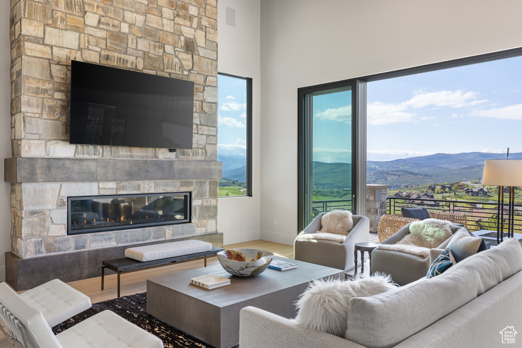 Living area with a mountain view, a stone fireplace, wood finished floors, and plenty of natural light