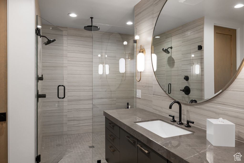 Bathroom with vanity, a stall shower, recessed lighting, and tile walls