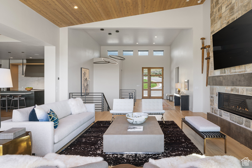 Living room with high vaulted ceiling, wood finished floors, wooden ceiling, recessed lighting, and a fireplace