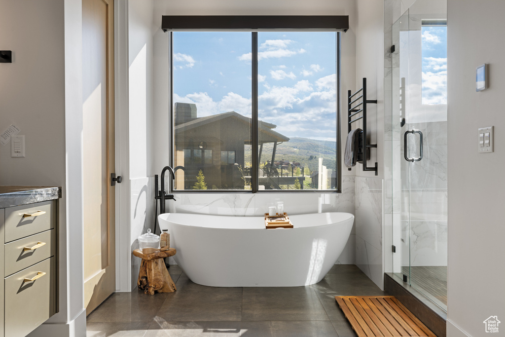 Bathroom with a soaking tub, tile walls, a shower stall, and tile patterned flooring