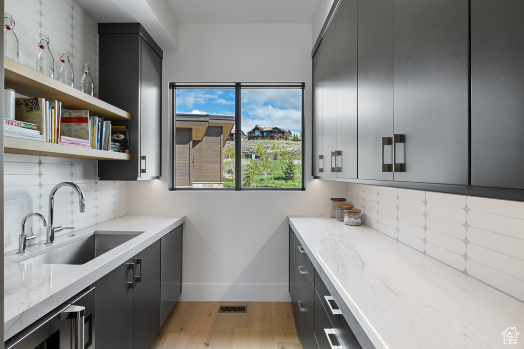 Kitchen featuring a sink, light wood-type flooring, baseboards, and backsplash