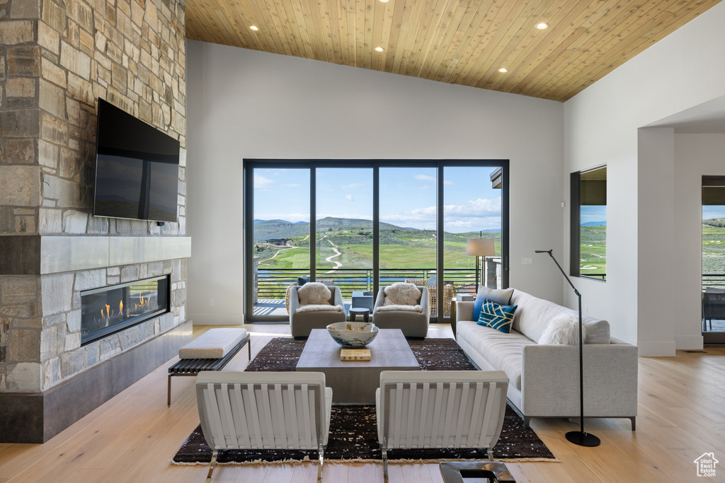 Living area with a fireplace, high vaulted ceiling, recessed lighting, wood finished floors, and wooden ceiling