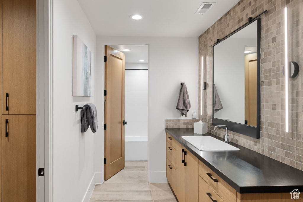 Bathroom with vanity, backsplash, recessed lighting, wood finished floors, and bathtub / shower combination