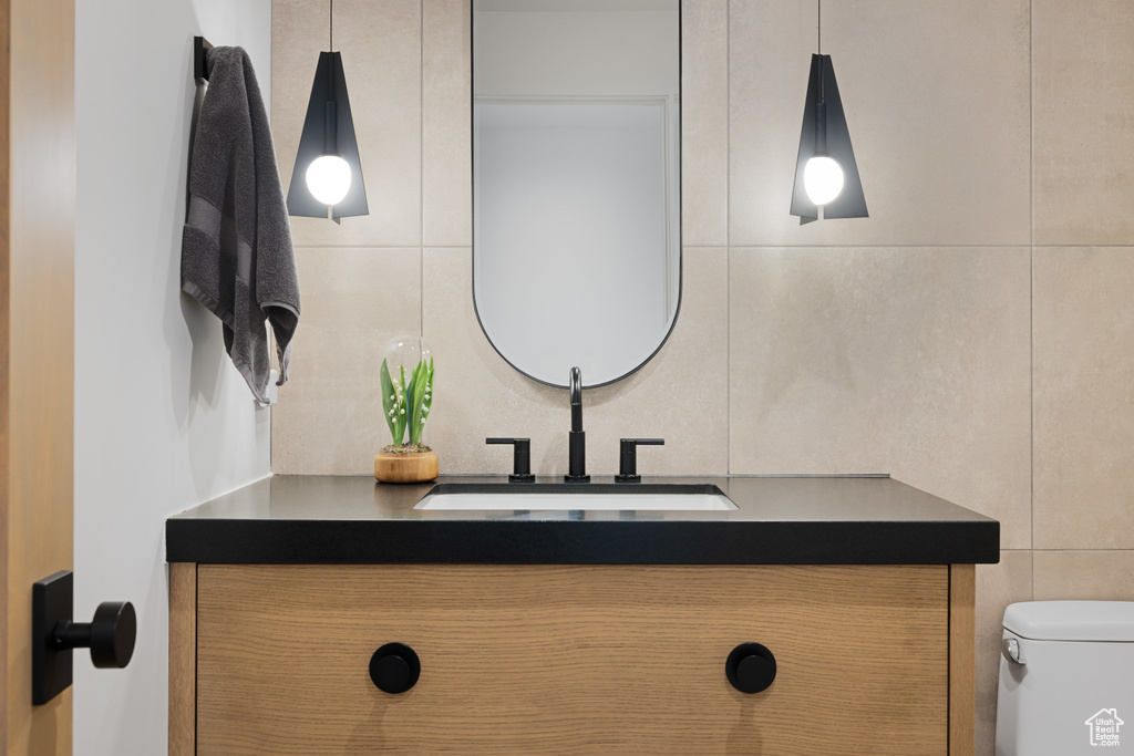 Bathroom featuring tile walls, toilet, and vanity
