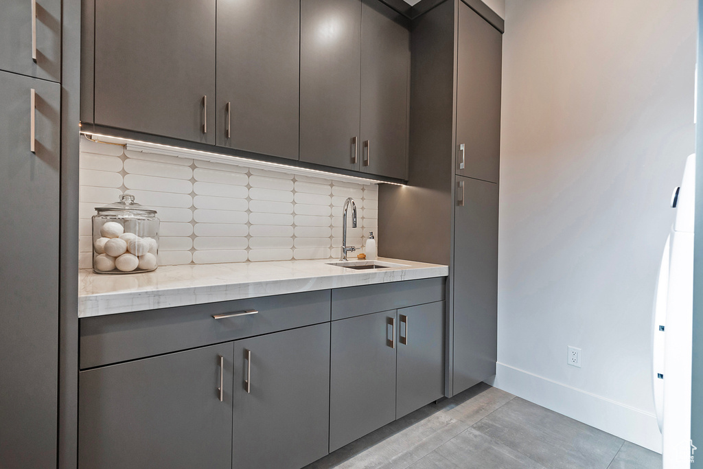 Bar area with a sink, tasteful backsplash, and baseboards