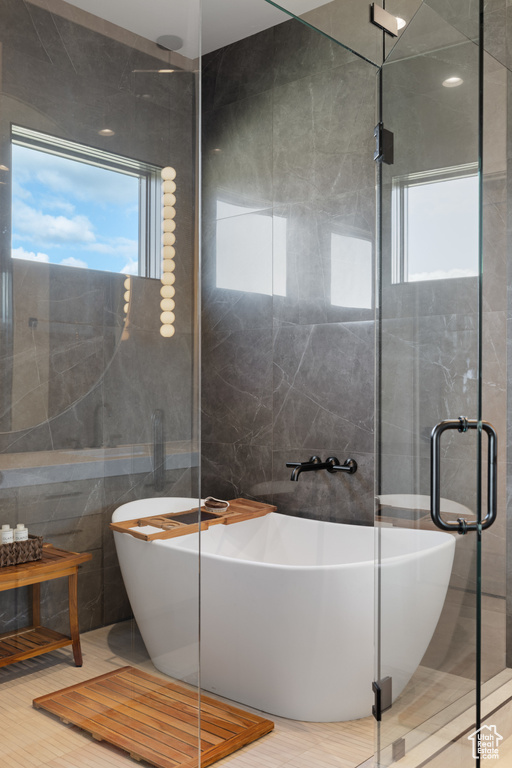 Bathroom with tile walls, a freestanding tub, and a shower stall