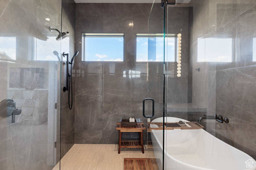 Full bathroom with a stall shower, a freestanding tub, and tile walls