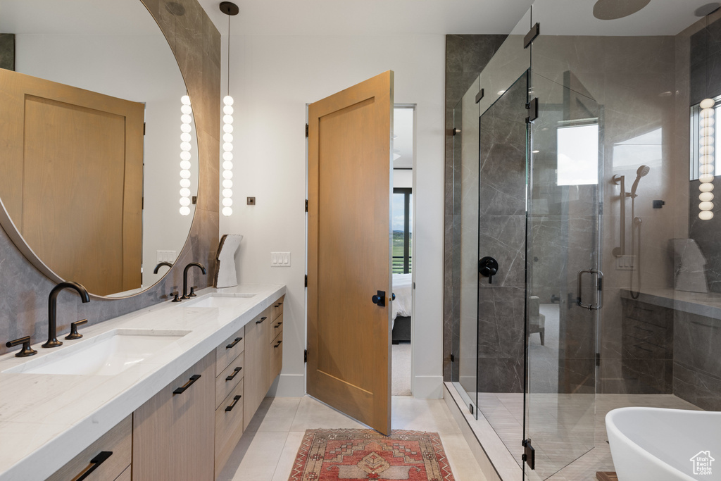Bathroom featuring double vanity, a stall shower, tile patterned floors, and a freestanding bath
