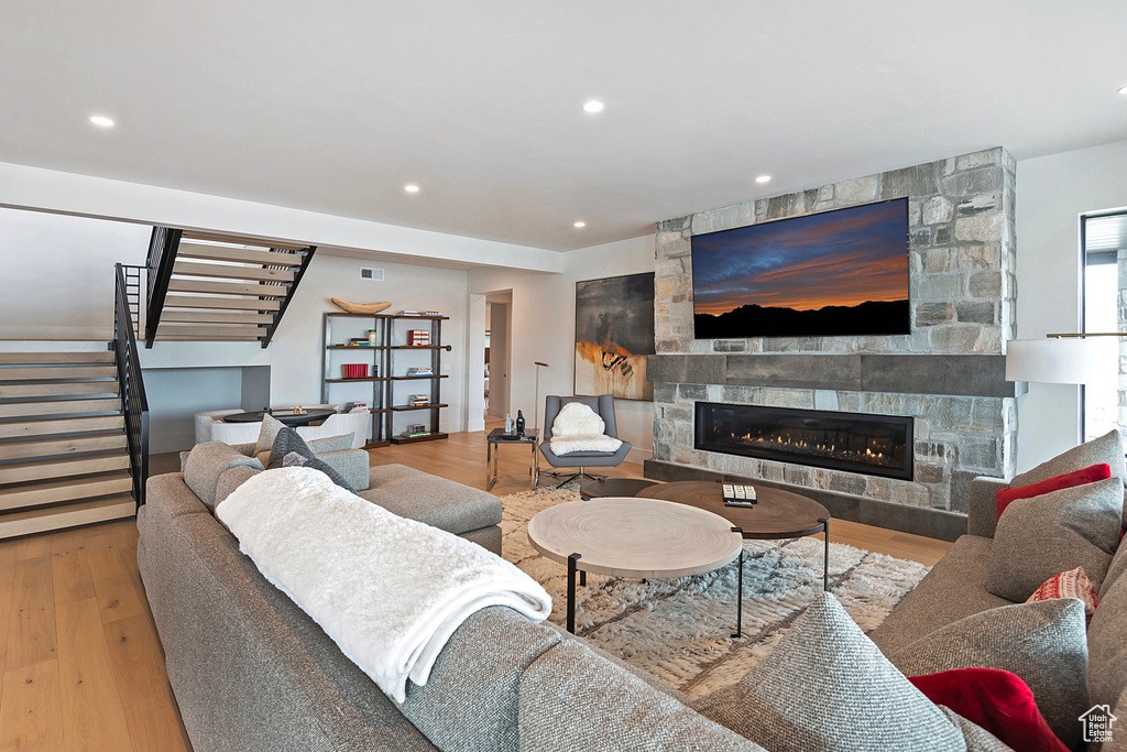 Living area with stairs, wood finished floors, a fireplace, and recessed lighting