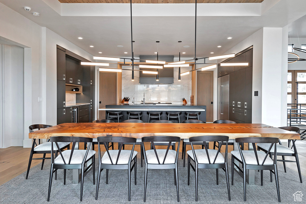 Kitchen featuring a tray ceiling, a center island, tasteful backsplash, light wood-style floors, and recessed lighting