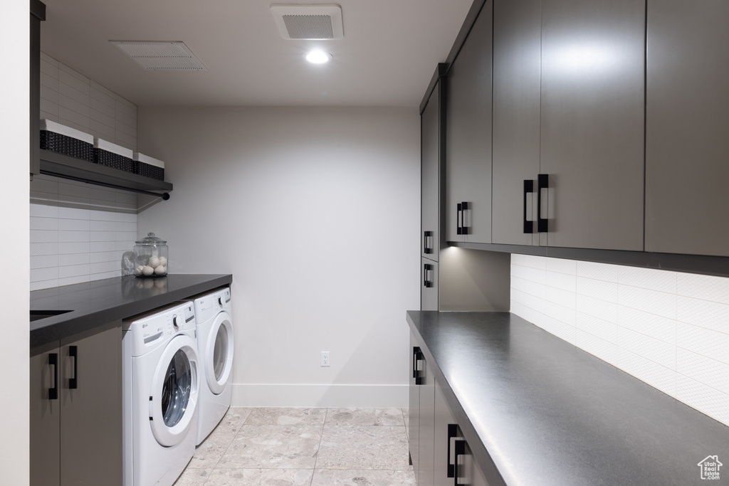 Washroom with separate washer and dryer, baseboards, and cabinet space