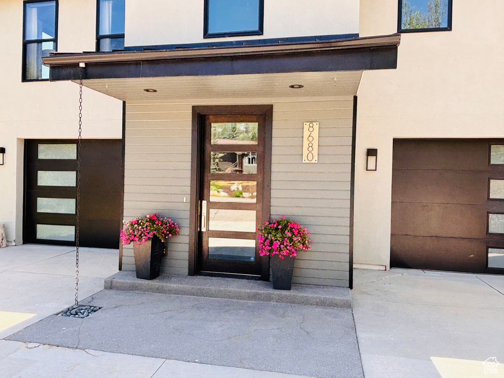 View of exterior entry with an attached garage and stucco siding