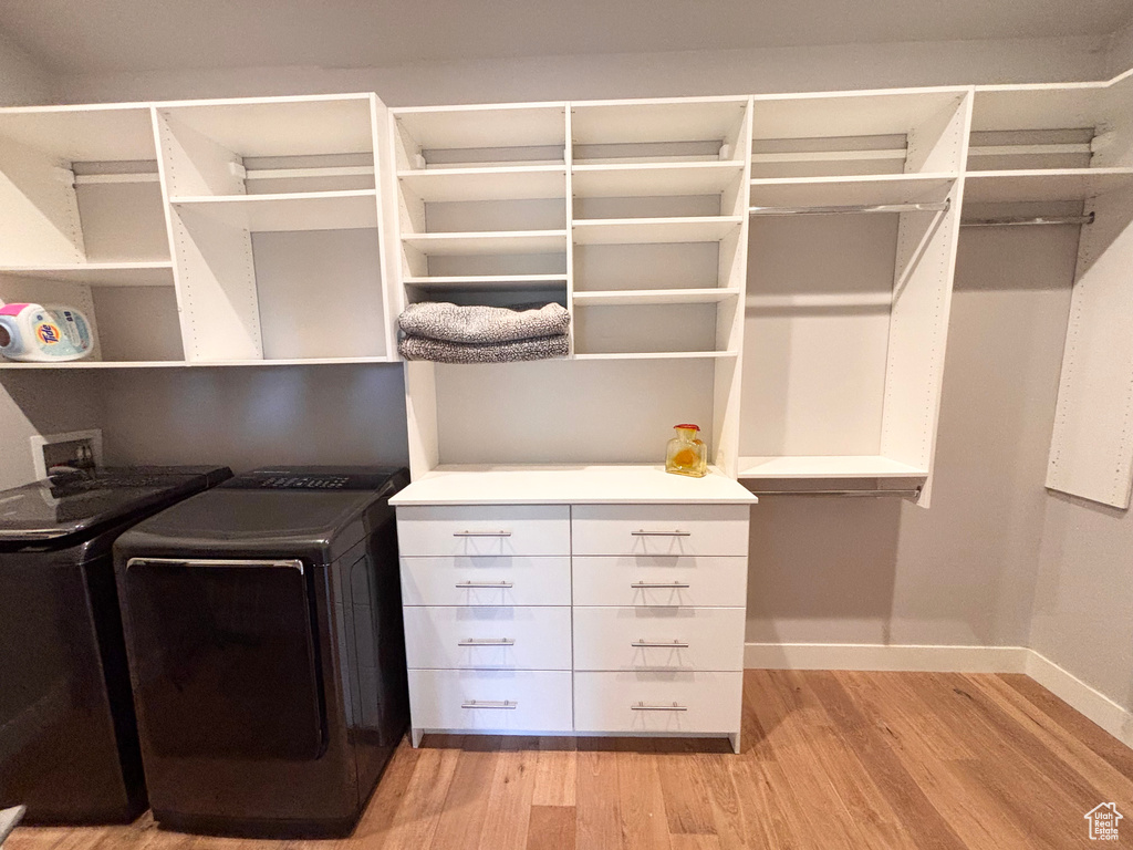 Spacious closet with separate washer and dryer and light wood-type flooring