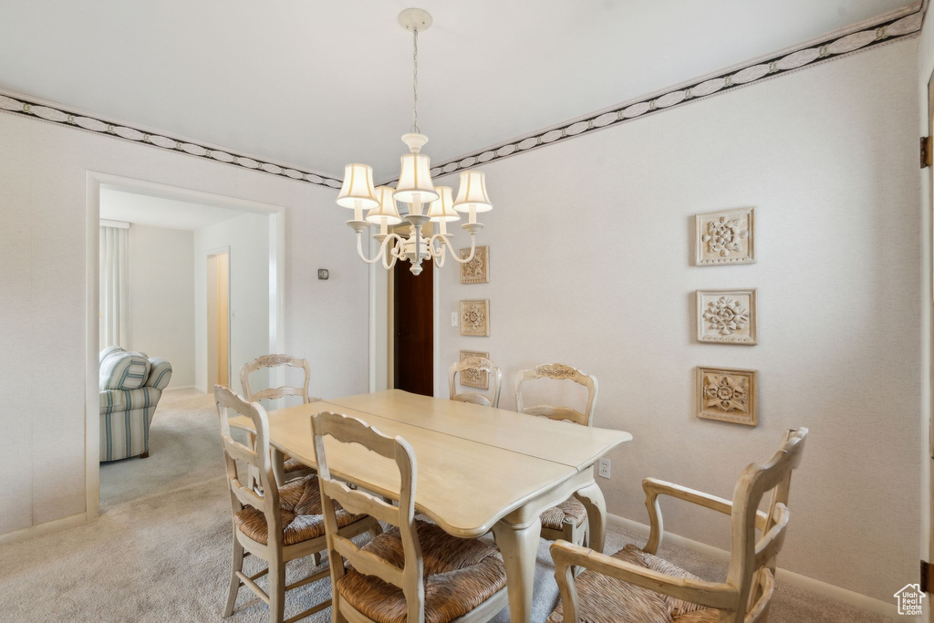 Dining area featuring a notable chandelier, baseboards, and light colored carpet