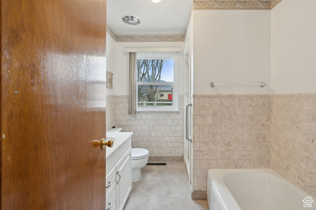 Bathroom with tile walls, toilet, a tub to relax in, an enclosed shower, and wainscoting