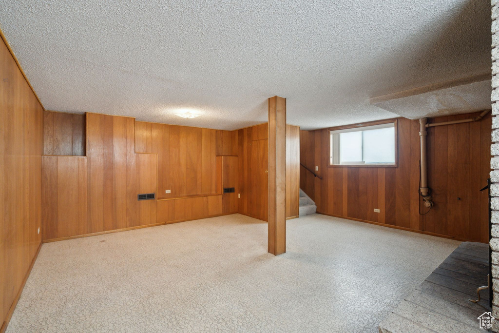 Below grade area featuring baseboards, wood walls, stairway, and a textured ceiling