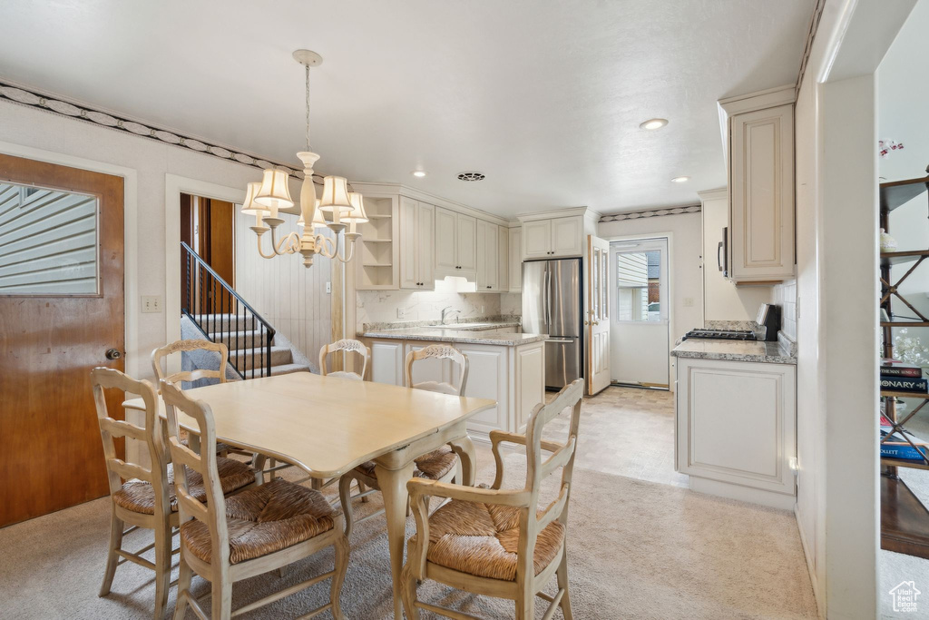 Dining room with light colored carpet, a notable chandelier, stairs, and recessed lighting