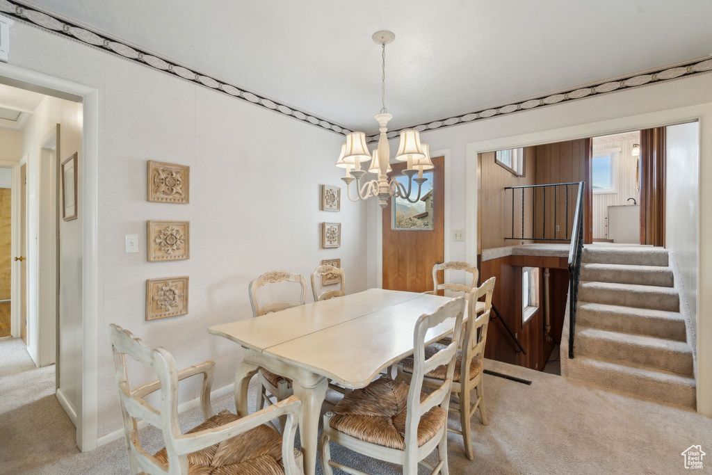 Dining room featuring baseboards, a chandelier, stairway, and light colored carpet