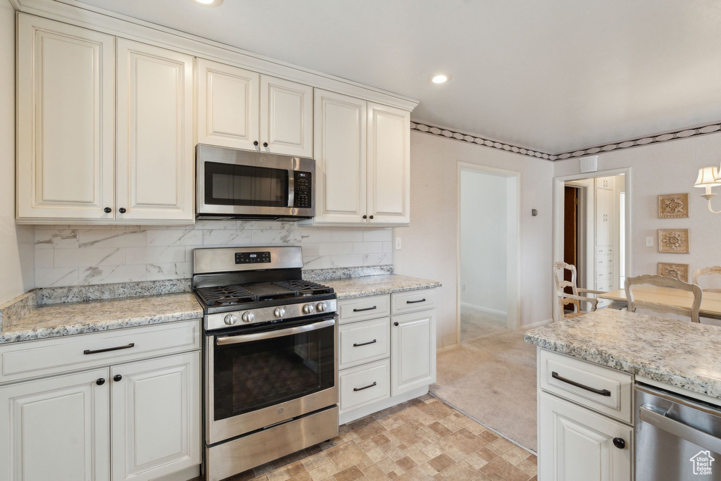 Kitchen featuring light stone countertops, stainless steel appliances, tasteful backsplash, and recessed lighting