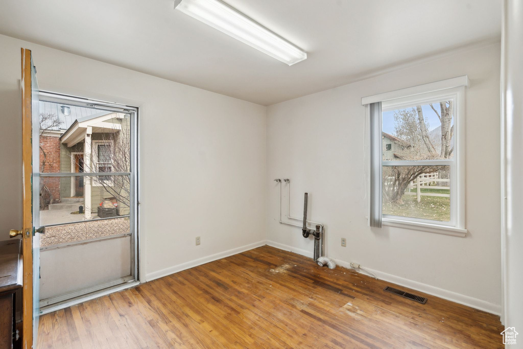 Unfurnished room with wood finished floors, baseboards, and visible vents