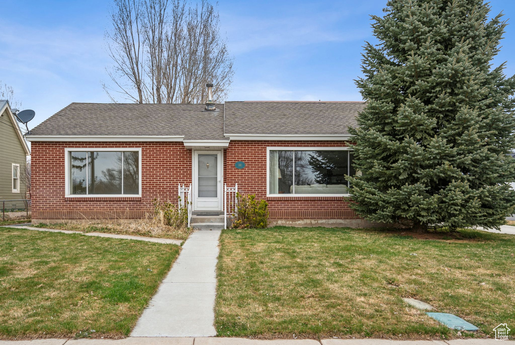 Single story home with brick siding, a shingled roof, and a front yard