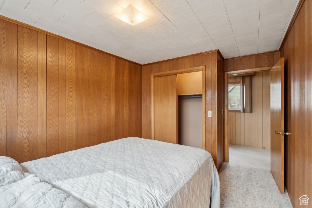 Bedroom with a closet, wooden walls, and carpet