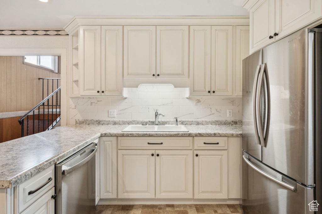 Kitchen featuring backsplash, cream cabinetry, a sink, and appliances with stainless steel finishes