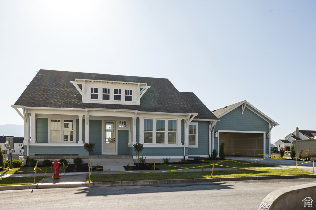 View of front facade with an attached garage, driveway, a front yard, and a shingled roof