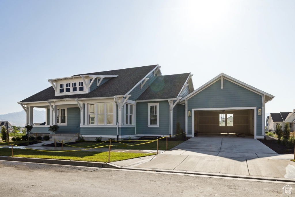 View of front of home featuring an attached garage, driveway, a front lawn, and a shingled roof