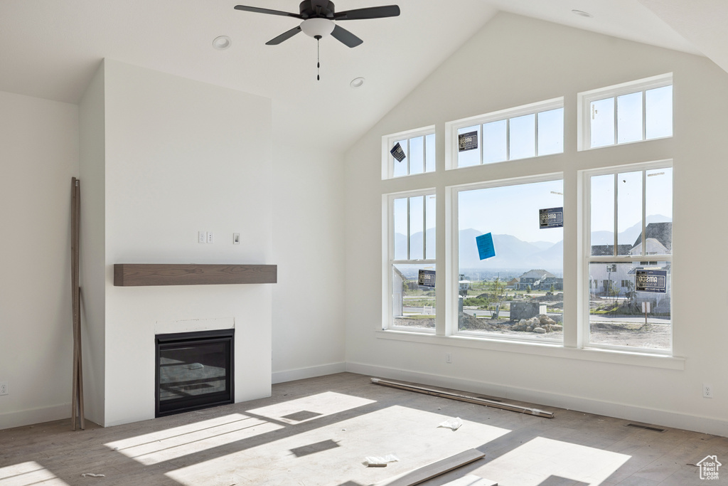 Unfurnished living room featuring a ceiling fan, a glass covered fireplace, high vaulted ceiling, and wood finished floors