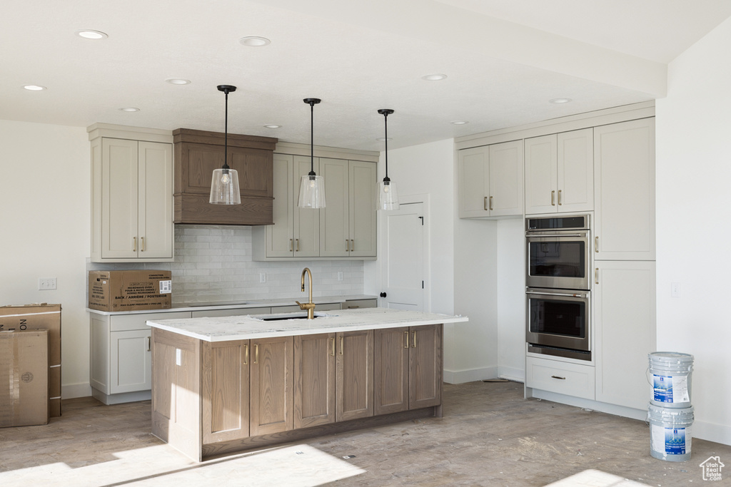 Kitchen featuring double oven, tasteful backsplash, recessed lighting, black electric stovetop, and a center island with sink